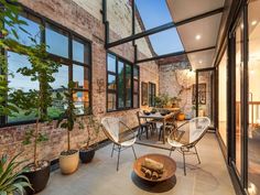 a patio with chairs, tables and potted plants on the side of the building