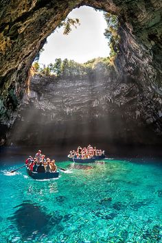 a group of people are in a boat going through a cave with blue water and sunlight coming from the ceiling