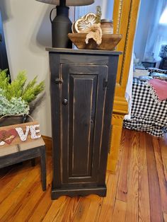 a black cabinet sitting on top of a hard wood floor next to a table with a lamp