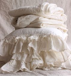 a pile of white linens stacked on top of each other with ruffled edges