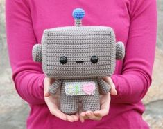 a person holding a small crocheted toy in their hands