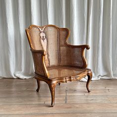 an old chair with a deer head on it's back and arm rests in front of a white curtain