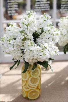 a yellow vase filled with white flowers and lemon slices