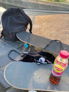 a skateboard is sitting on the ground next to a backpack and bottle of water