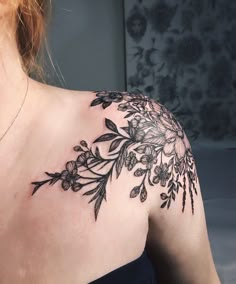 a woman's shoulder with flowers on it and leaves around the neck, in black ink