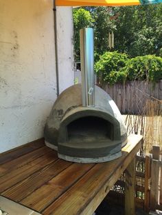 an outdoor pizza oven sitting on top of a wooden table