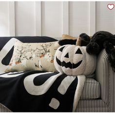 a black and white pumpkin pillow sitting on top of a couch next to a stuffed animal