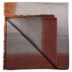 an orange, grey and white blanket with fringes on the edges is folded up