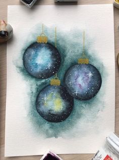 a watercolor painting of three christmas ornaments on top of a white piece of paper