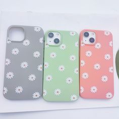 three iphone cases with flowers on them sitting next to an apple watch and earphones