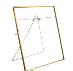 a gold metal frame with a square and triangle design on the bottom, in front of a white background