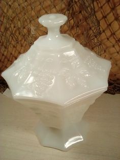 a white glass vase sitting on top of a wooden table