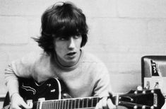 black and white photograph of a young man playing an acoustic guitar