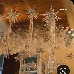 some white and silver balloons hanging from the ceiling in front of a window with stars on it