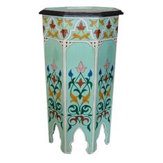 an ornately painted side table with flowers and leaves on the top, against a white background