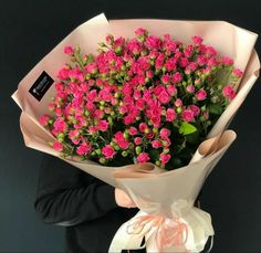 a person holding a bouquet of pink flowers