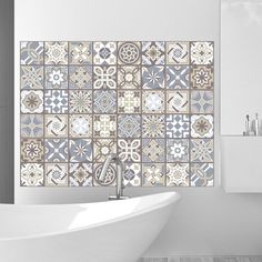 a bath tub sitting next to a white sink in a bathroom under a tiled wall