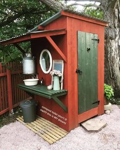 a red shed with a green door next to a tree