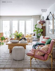 a living room filled with lots of furniture and plants on the wall next to large windows