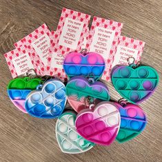 several heart shaped key chains with tags attached to them on a table next to some cards