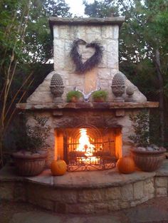 an outdoor fireplace with potted plants and pumpkins on the mantle next to it