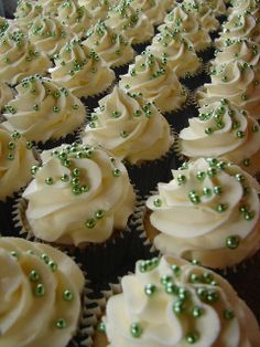 many cupcakes with white frosting and green sprinkles on them