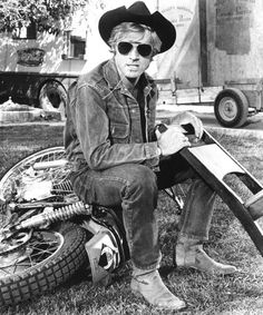 a man sitting on top of a motorcycle next to a pile of junk and other items