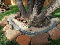 a toy train set sitting under a tree