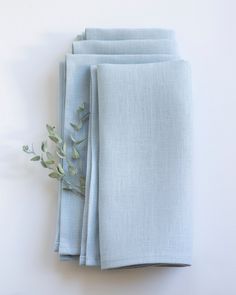 four folded napkins on top of each other with a plant in the middle one