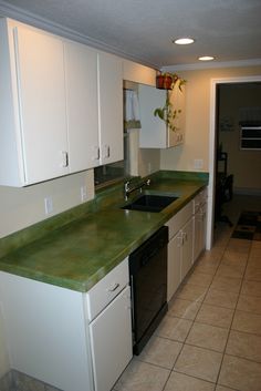 an empty kitchen with white cabinets and green counter tops on the island in front of the dishwasher