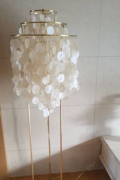 a lamp that is sitting on top of a wooden floor next to a wall with white flowers