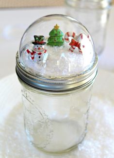 a glass jar filled with snowmen sitting on top of a table