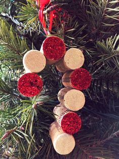 some corks are hanging from a christmas tree with red ornaments on them and one is made out of wine cork