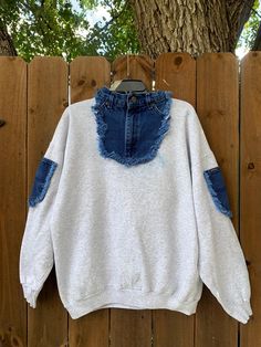 a white and blue sweater hanging on a wooden fence with a tree in the background