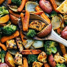 a wooden spoon filled with roasted potatoes and broccoli