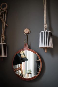 a mirror hanging from the side of a wall next to two lamps and a lamp shade