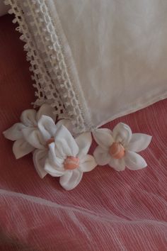 two white flowers sitting on top of a bed next to a pillow