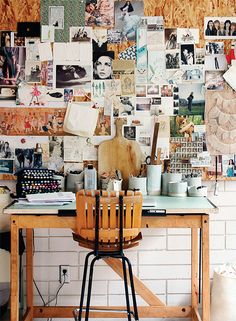 a wooden table sitting in front of a white brick wall covered in pictures and photos