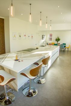 a kitchen with white counter tops and bar stools