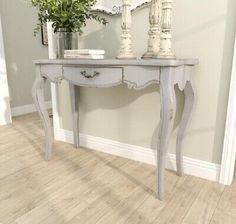 a white table with two vases on top of it and a mirror above it