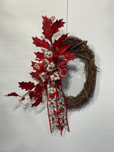 a wreath with red and green leaves hanging on a wall