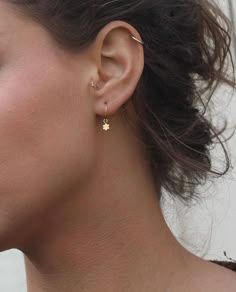 a close up of a woman's face wearing gold earring and nose piercings