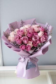 a bouquet of pink roses wrapped in purple paper