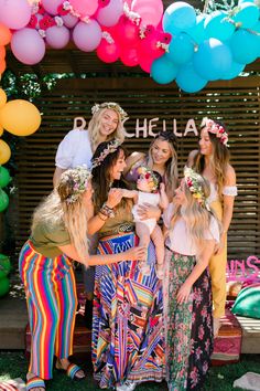 a group of women standing next to each other in front of a bunch of balloons