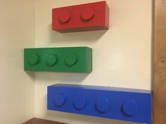 three legos are hanging on the wall next to each other, one is blue and one is red