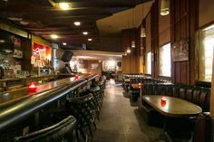 the interior of a restaurant with leather booths and bar stools, along with wood paneled walls