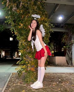 a woman dressed as a fairy standing next to a tree