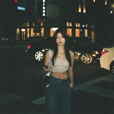 a woman is standing on the street at night with her cell phone in her hand