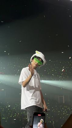 a young man standing on top of a stage holding a cell phone to his ear