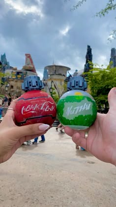 two people holding up small balls with coca cola on them